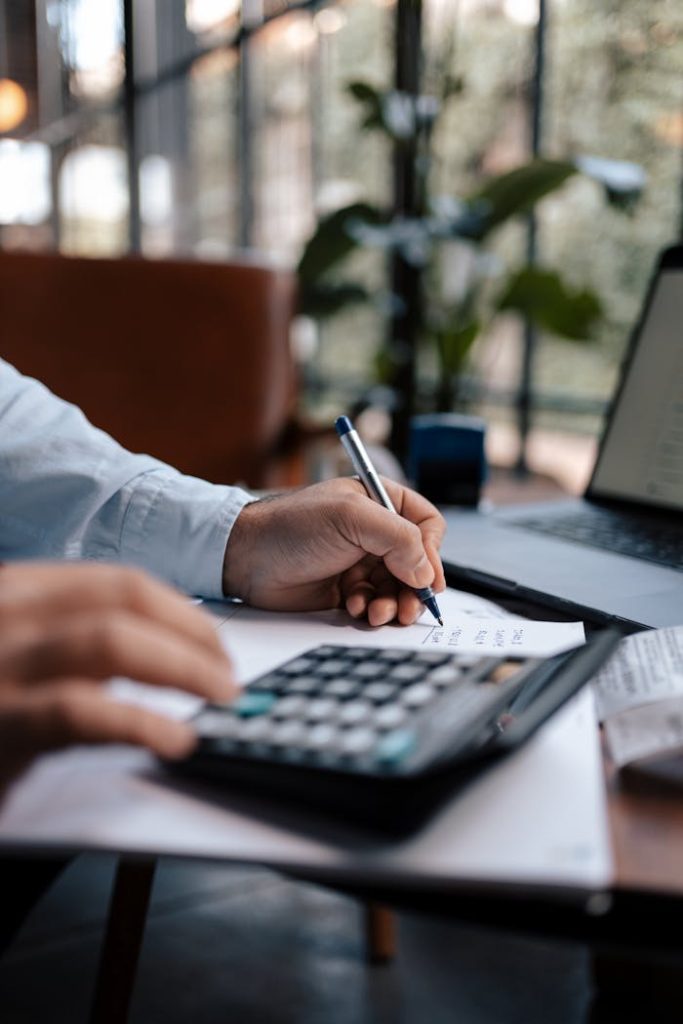 a-person-using-a-calculator-16282306 A person calculating finances with a calculator and pen on a desk indoors.